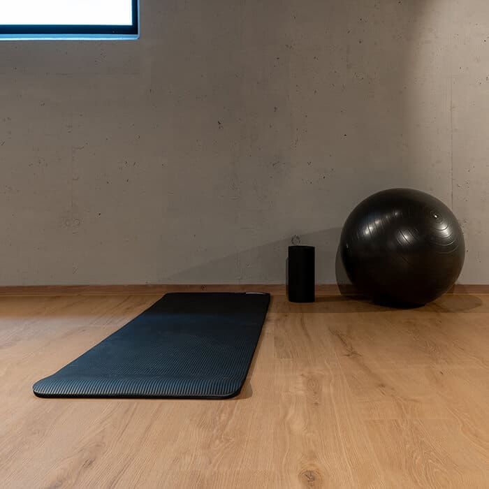 Fitnessraum mit Designboden Ebenbild Dekor Taunus, Gymnastikmatte, Ball und Faszienrolle vor Spiegelwand