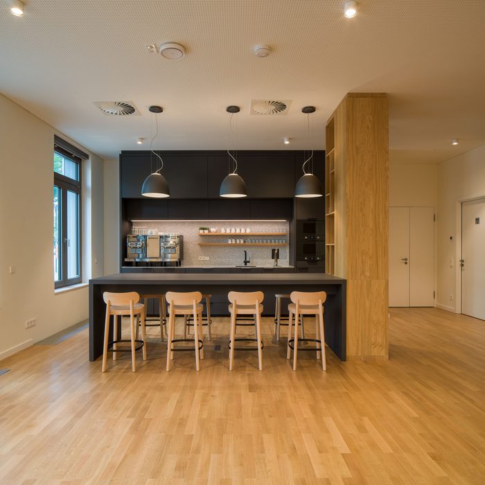 Moderne Küche mit Parkett, schwarzer Theke und Holzstühlen